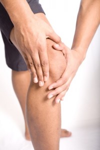 knee pain, woman holding her knee in pain