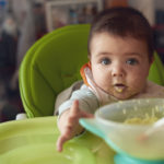 Infant with baby food on their face during feeding time